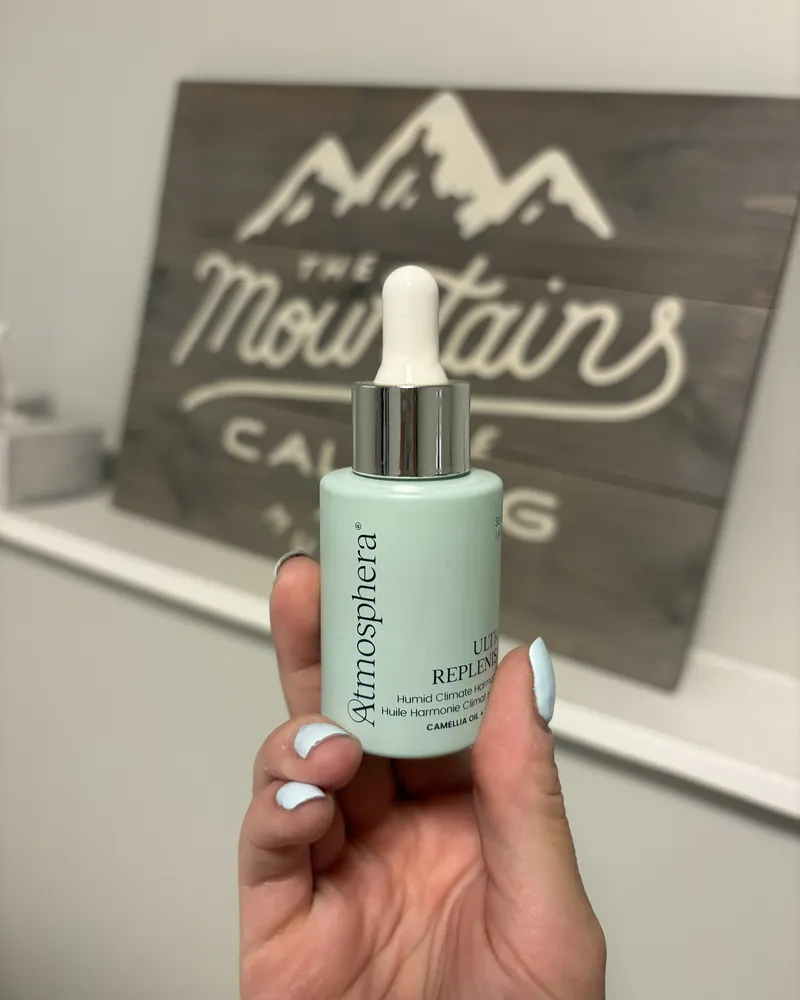 A customer's photo: a bottle of ULTRA REPLENISH™ held up in front of a wooden sign with mountains painted on it.
